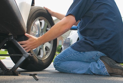 man removing a tire from vehicle